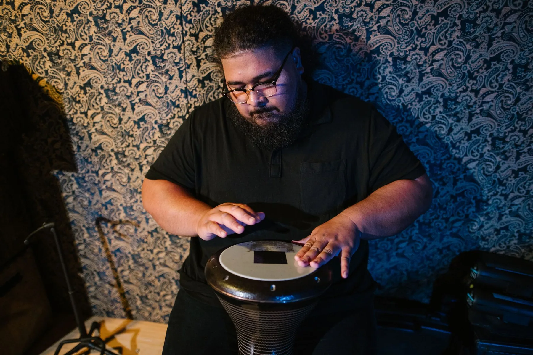 percussionist playing a djembe indoors percussionist playing a djembe indoors
